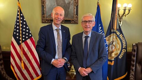 Bildungsminister Schwarz mit Tony Evers, Gouverneur des Bundesstaates Wisconsin Bildungsminister Schwarz und Tony Evers stehen in einem Raum vor unter anderem der US-amerikanischen Flagge.