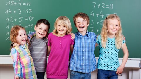 Grundschulkinder stehen vor einer Tafel