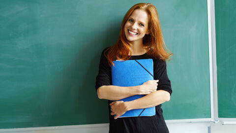 Junge Lehrerin steht vor einer Tafel 