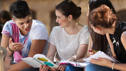 Schülerinnen und Schüler schauen gemeinsam in Schulbücher Schülerinnen und Schüler schauen gemeinsam in Schulbücher