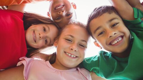 Kinder stehen in einem Kreis und schauen nach unten in eine Kamera