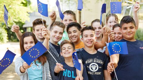 Schülerinnen und Schüler schwenken kleine EU-Fahnen. Schülerinnen und Schüler schwenken kleine EU-Fahnen.