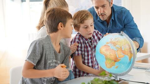 Lehrer schaut mit Schülerinnen und Schülern auf einen Globus. Lehrer schaut mit Schülerinnen und Schülern auf einen Globus.