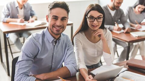 Junger Mann und junge Frau sitzen gemeinsam im Unterricht. 