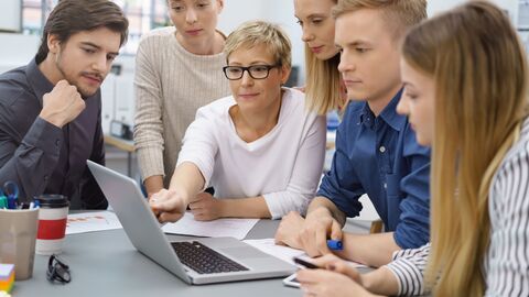 Lehrerin zeigt einer Gruppe von jungen Menschen etwas an einem Laptop. Lehrerin zeigt einer Gruppe von jungen Menschen etwas an einem Laptop.