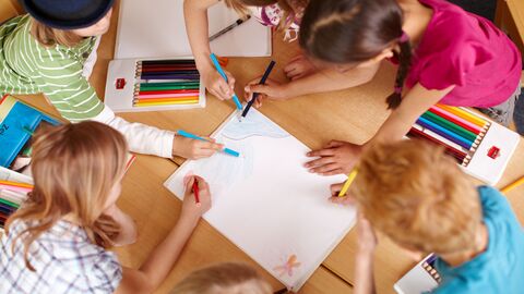 Grundschulkinder malen gemeinsam ein Bild.