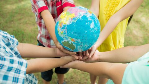 Schülerinnen und Schüler halten einen Globus in ihren Händen.