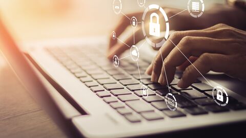 Am Laptop schreibende Hände mit Datenschutzsymbol.