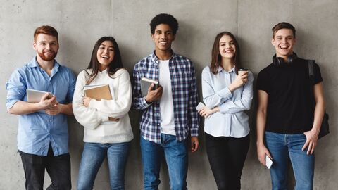 Junge Menschen stehen vor einer grauen Wand. 