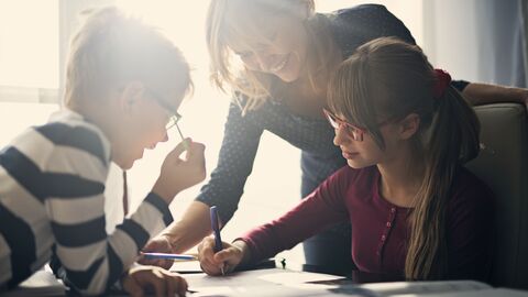 Mutter hilft ihren Kindern bei den Hausaufgaben.