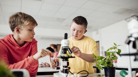 Zwei Jungen bereiten ein Mikroskop für den Unterricht vor. 