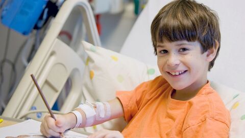 Ein Junge sitzt in einem Krankenhaus in einem Bett und malt.
