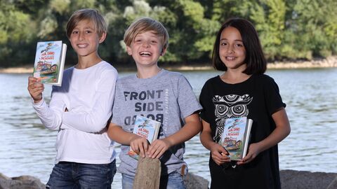 Drei Kinder mit dem Comicroman „Iva, Samo und der geheime Hexensee“ zum Welttag des Buches 2022. Drei Kinder mit dem Comicroman „Iva, Samo und der geheime Hexensee“ zum Welttag des Buches 2022.