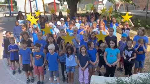 Schüler und Schülerinnen der Rosendorfschule singen in blauen T-Shirts und gelben Sternen 