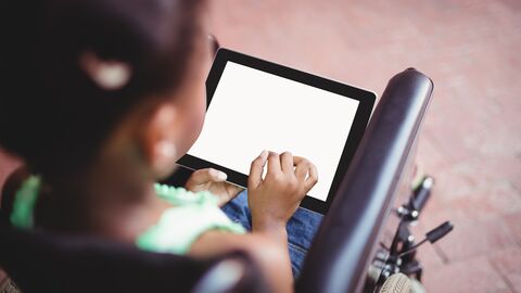 Ein Mädchen, das in einem Rollstuhl sitzt, kommuniziert mit einem Tablet. Ein Mädchen, das in einem Rollstuhl sitzt, kommuniziert mit einem Tablet.