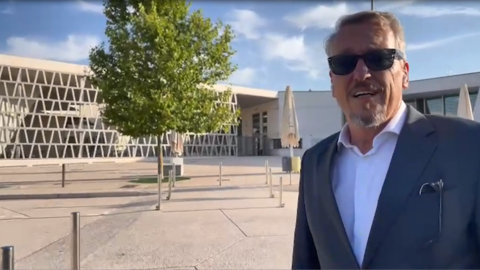 Schulleiter Dirk Pilgram vor dem Gebäude der Deutschen Schule Madrid, man sieht den großen Hof und die Architektur des Baus.