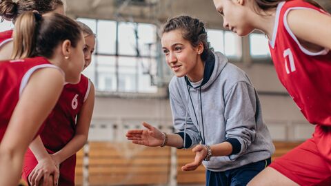 Ein Mädchen-Baseketball-Team wird von einer jungen Trainierin angefeuert. Ein Mädchen-Baseketball-Team wird von einer jungen Trainierin angefeuert.