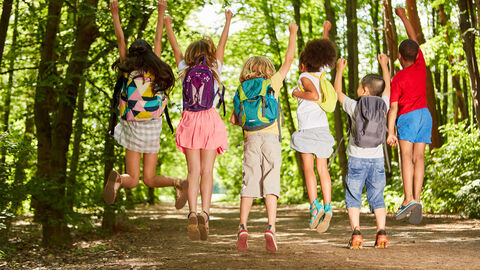 Kinder springen bei einem Schulausflug in die Luft.