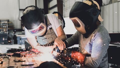 Zwei Schülerinnen einer beruflichen Schule schweißen Metall zusammen. 