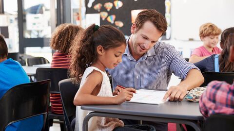 Lehrer zeigt Schülerin etwas im Buch