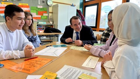 Kultusminister Lorz mit Schülerinnen und Schülern Kultusminister Lorz sitzt mit vier Schülerinnen und Schülern um einen Tisch voll Schulmaterial.