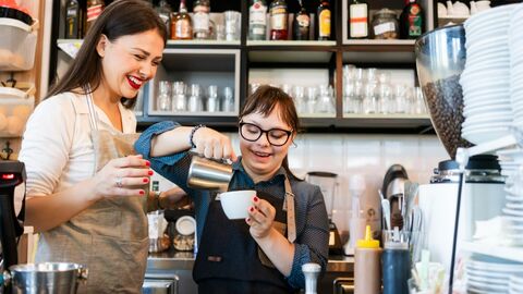 Junge Frau mit Downsyndrom bereitet Kaffee zu Junge Frau mit Downsyndrom bereitet Kaffee zu