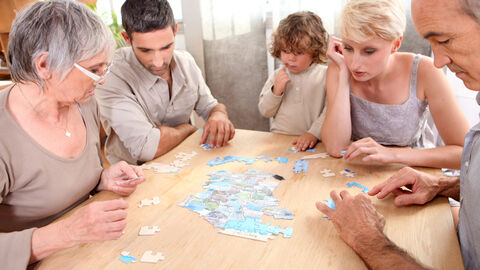 Mehrere Generationen einer Familie puzzeln gemeinsam.