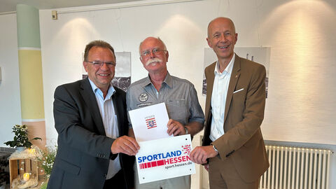 Bildungsminister Schwarz (rechts) steht neben Landrat Winfried Becker und 1. Beigeordneter Wolfgang Nelke. Er übergibt den Bescheid.