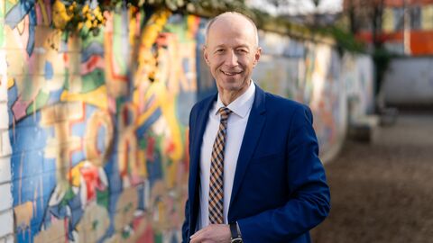 Mann im Anzug steht vor Graffiti-Wand