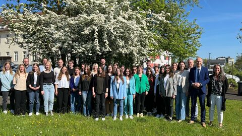 Eine Gruppe junger Personen steht gemeinsam mit Kultusminister Schwarz auf einer Wiese vor einem Baum zum Gruppenfoto.