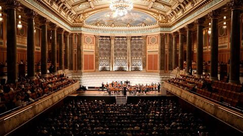 Blick in einen Theatersaal, auf der Bühne steht ein kleines Orchester.