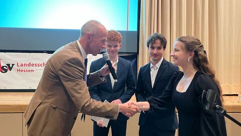 Jubiläumsfeier der Landesschülervertretung Kultusminister Armin Schwarz schüttelt einer Schülerin der Landesschülervertretung die Hand. Zwei weitere Schüler stehen im Hintergrund und lächeln freundlich.