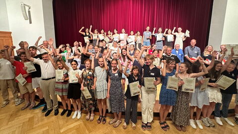 Preisverleihung zum Schulwettbewerb „Katta und Co im Opel-Zoo 3.0. Werde Botschafter für den Artenschutz!“ am 2. Juli im Festsaal der Stadthalle Kronberg im Taunus Über 50 Schülerinnen und Schüler stehen in einem Saal und jubeln.
