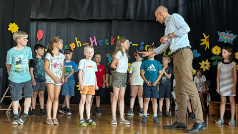 WERTvoll-Tour in Bensheim Armin Schwarz hält ein Mikrofon zu einer Schülerin - um sie herum viele weitere Schülerinnen und Schüler