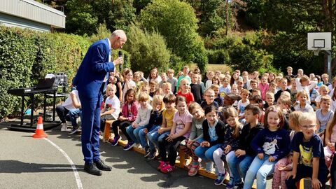 Kultusminister Armin Schwarz im Gespräch mit Kindern der Wigand-gerstenberg-Schule in Frankenberg. Kultusminister Armin Schwarz besucht am Aktionstag der Feuerwehr die Wigand-Gerstenberg-Schule in Frankenberg. Viele Schülerinnen und Schüler sitzen draußen auf den Bänken und hören ihm zu.
