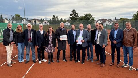 Mehrere Personen stehen auf einem Tennisplatz
