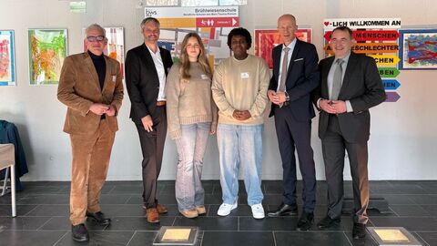 v.l.n.r.: Vorstand der Verbraucherzentrale Hessen, Philipp Wendt, Schulleiter der Brühlwiesenschule in Hofheim, Christoph Berg, Schülerin und Schüler der Brühlwiesenschule in Hofheim, Bildungsminister Armin Schwarz, Finanzminister Prof. Dr. Alexander Lorz Sechs Personen stehen in einem Schulgebäude nebeneinander und schauen in die Kamera