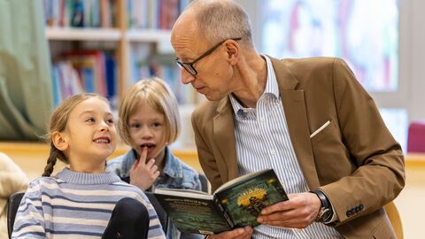 Bildungsminister Schwarz sitzt neben einem Mädchen und liest vor.