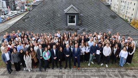 Eine große Gruppe von Menschen stehen auf einem großen Balkon - Fotografiert aus der Vogelperspektive.