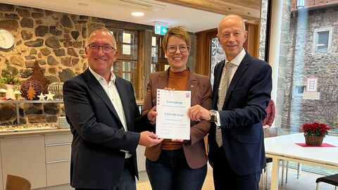 Zwei Männer und eine Frau stehen nebeneinander und halten gemeinsam einen Förderbescheid in den Händen