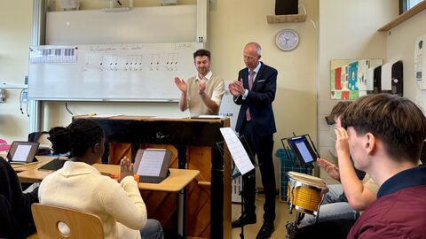 Bildungminister Schwarz steht in einer Schulklasse vorne neben einem Lehrer.