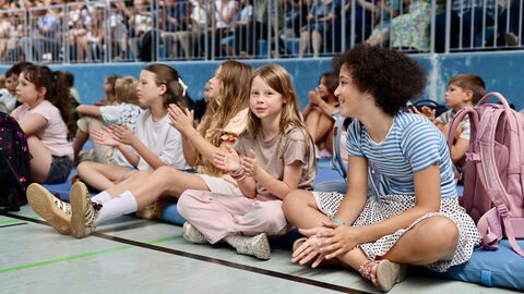 Kinder sitzen auf dem Boden einer Sporthallte